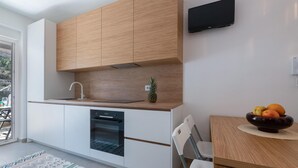 Une cuisine moderne avec des meubles en bois, un four encastré et un coin repas comprenant une table et des chaises.