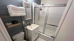 Een kleine badkamer met toilet, wastafel en douche.