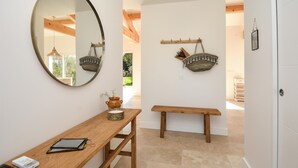 A hallway with a wooden bench, a round mirror, and two wall-mounted baskets. - Amazing home in Serignan (Serignan)