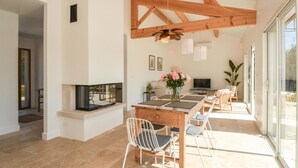 A modern dining area with a wooden table, white chairs, and a fireplace. - Amazing home in Serignan (Serignan)