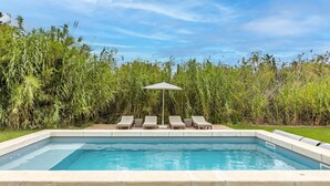 A rectangular swimming pool with a concrete edge, surrounded by lounge chairs and a single umbrella. - Amazing home in Serignan (Serignan)