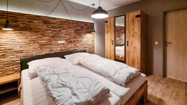 Una camera da letto con una testiera in legno, un letto con biancheria bianca, un armadio in legno e uno specchio.