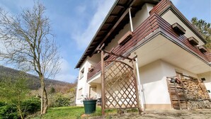 Un tipico chalet con tetto spiovente, cancello in legno intagliato e parete in pietra.