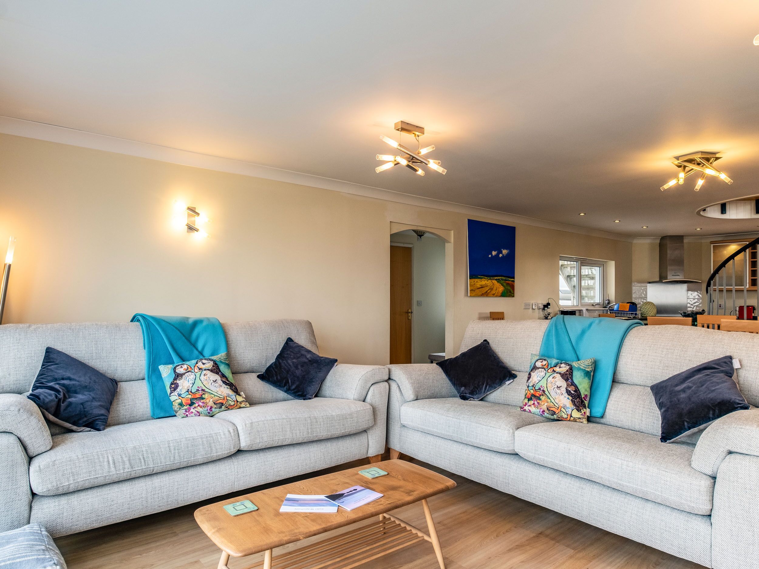 A living room with two grey sofas, a wooden coffee table, and a painting on the wall.