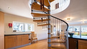 Une cuisine moderne avec un escalier en colimaçon, des meubles en bois et une grande fenêtre.