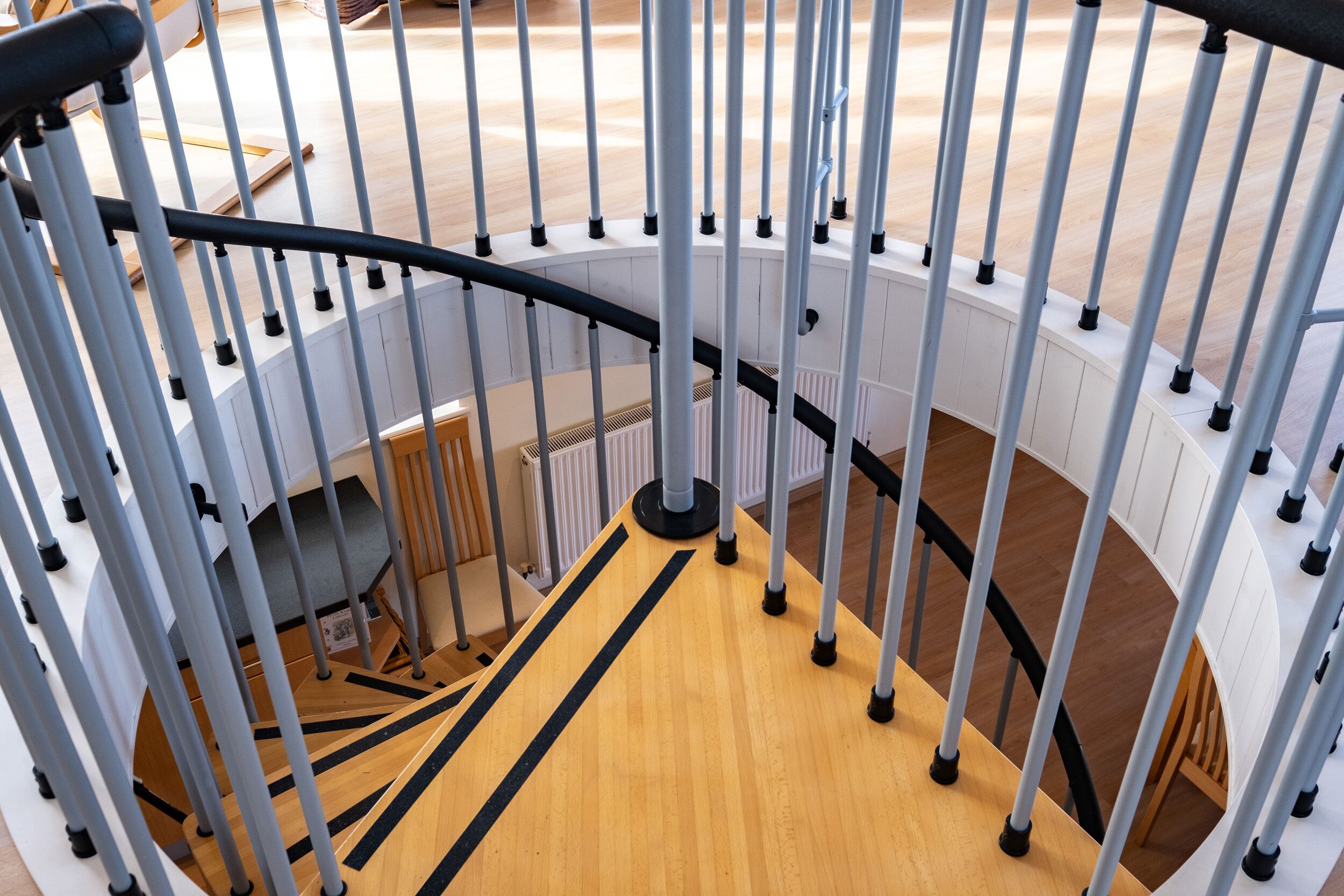 A spiral staircase with a wooden finish and metal railings.