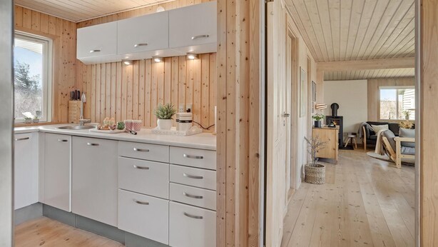 A modern kitchen with wooden paneling, white cabinets, and a built-in stove. - 3 bedroom nice home in Løkken (Løkken)