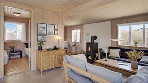 A cozy cabin interior with a wooden ceiling, a fireplace, a sofa, a coffee table, and a dining area. - 3 bedroom nice home in Løkken (Løkken)