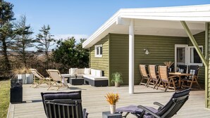 A covered outdoor deck with a sofa, chairs, and a dining table. - 3 bedroom nice home in Løkken (Løkken)