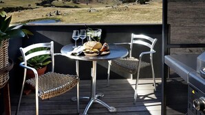 A patio with two metal chairs, a small round table, and a grill. - Farm stay accomodation (Pyalong)