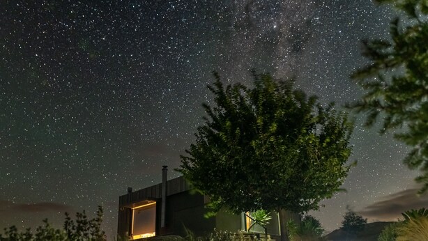 A house with a stone staircase leading up to a door, surrounded by greenery and a starry night sky. - Farm stay accomodation (Pyalong)