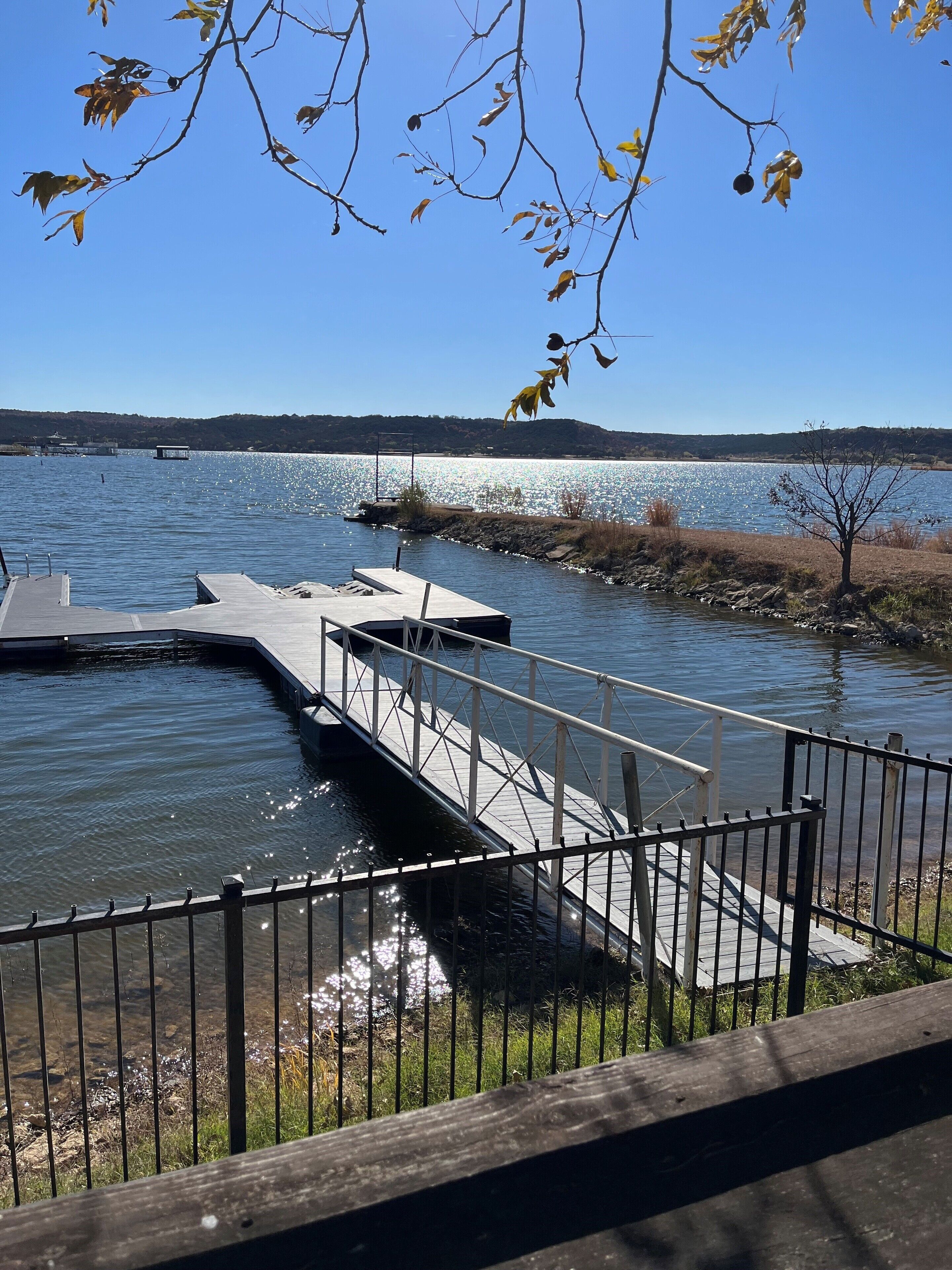 A wooden dock extending into a calm lake with a clear sky above.