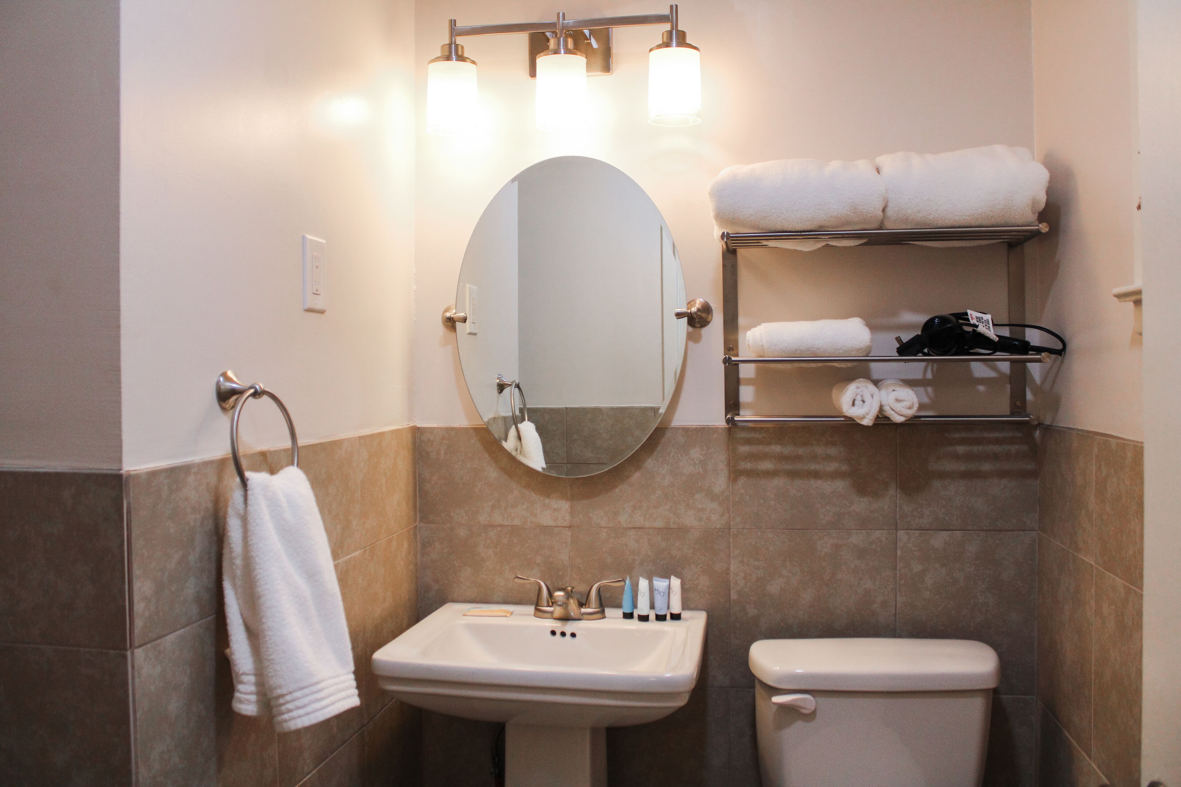 A bathroom with a sink, toilet, and a towel rack with towels.
