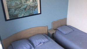 A room with two beds, a nightstand, and a framed painting on the wall. - Hardelot Apartment Panoramic beach and sea view (Neufchâtel-Hardelot)