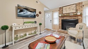 Ein Wohnzimmer mit Fernseher, Kamin und einer Konsole mit Dekoration.