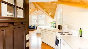Una cocina moderna con armarios blancos, estufa y techo de madera.