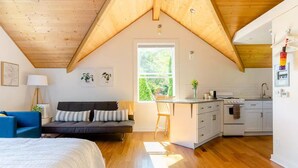 Un dormitorio estilo loft acogedor, con una cama grande, un escritorio y un kitchenette.