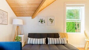 Una sala de estar moderna con un sofá, una lámpara y obras de arte enmarcadas en la pared.
