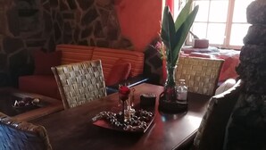 Ein Essbereich mit Steinwand, Korbmöbeln und einem Tisch, gedeckt mit einem Glas, einer roten Rose und einer Schokoladentafel.