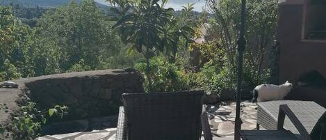 A patio with stone flooring, a wicker chair, a table, and an umbrella.