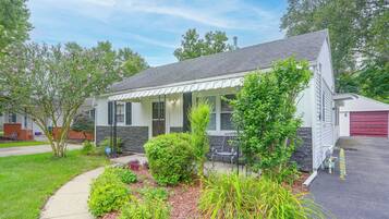 A single-story house with a covered porch, a garage, and a well-maintained garden with various plants and shrubs.