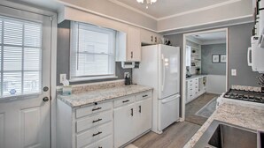 A compact kitchen with white cabinets, a refrigerator, a stove, and a ceiling fan. - 8 Mi to Lake Eerie & Dtwn Toledo! Peaceful Cottage (Toledo)