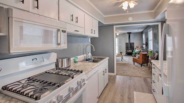 A modern kitchen with white cabinets, a built-in microwave, a gas stove, and a sink. - 8 Mi to Lake Eerie & Dtwn Toledo! Peaceful Cottage (Toledo)