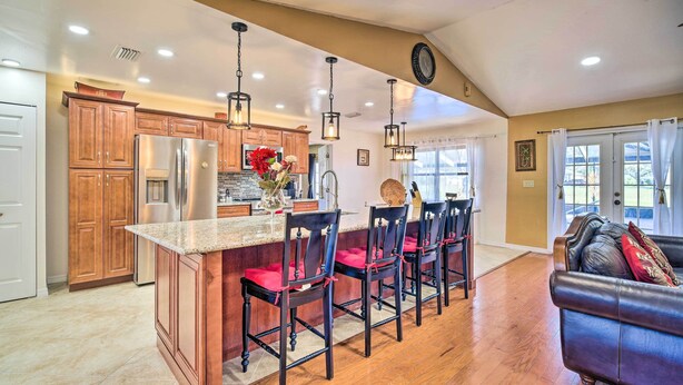 A spacious kitchen with wooden cabinets, a central island with bar stools, and pendant lighting. - Lanai, Pool & Gas Grill: Sebring Retreat! (Sebring)