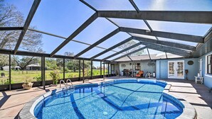 A covered swimming pool with a clear view of the surrounding area, including a house and a lawn. - Lanai, Pool & Gas Grill: Sebring Retreat! (Sebring)
