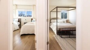 Ein Schlafzimmer mit Baldachinbett, einem Einzelbett und einem großen Fenster.
