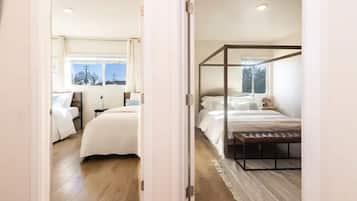 Een slaapkamer met een hemelbed, een apart bed en een groot raam.