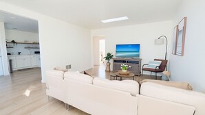 Ein modernes Wohnzimmer mit einem beigefarbenen Ecksofa, einem Couchtisch und einem Flachbildfernseher.