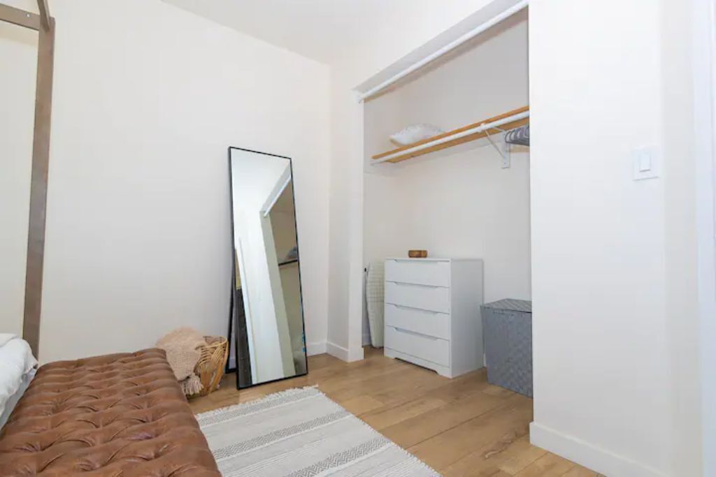 A bedroom with a bed, a large mirror, a wardrobe, and a dresser.