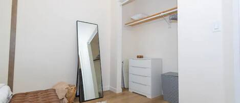 A bedroom with a bed, a large mirror, a wardrobe, and a dresser.