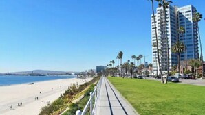 Eine Küstenpromenade mit Strand, Palmen und hohen Gebäuden im Hintergrund.