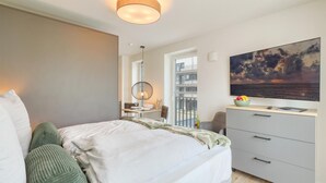 Une chambre à coucher moderne avec un lit, un bureau et une grande fenêtre.