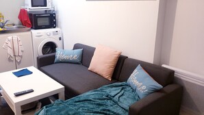 A compact living space with a sofa, a small table, a washing machine, and a microwave. - Magnificent F2 with terrace and parking, close to a park and 7 minutes from station (Le Mée-sur-Seine)