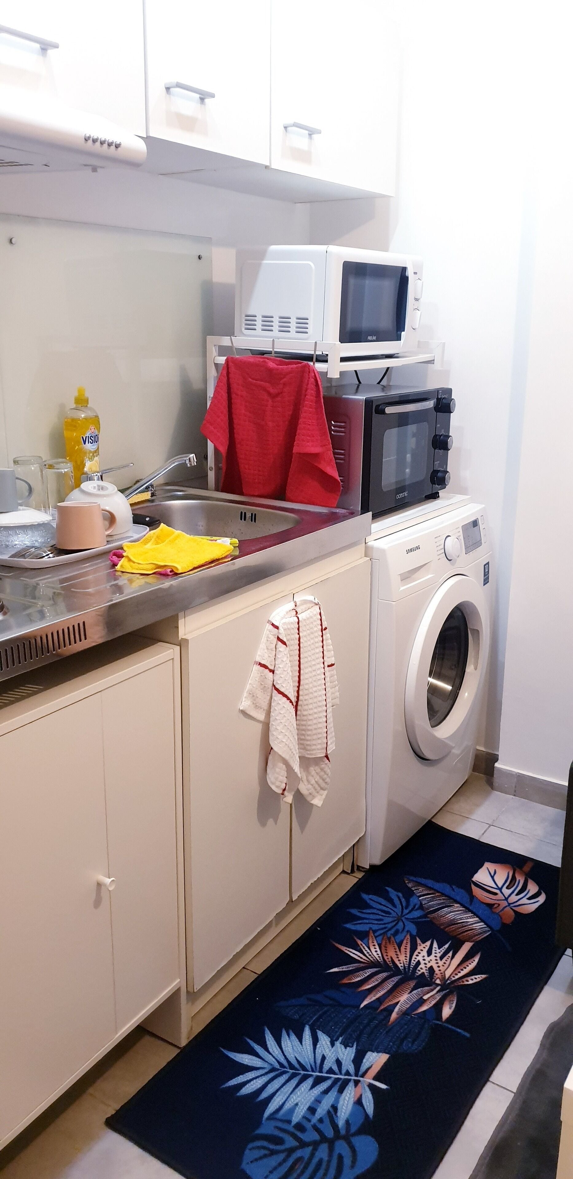 A compact kitchen with a microwave, toaster, and washing machine.