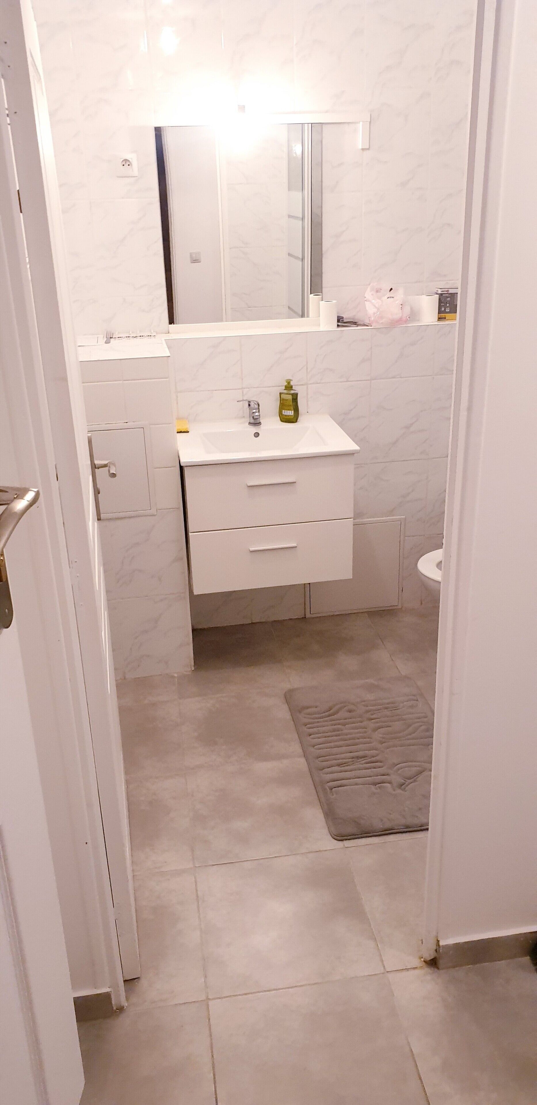 A bathroom with a white marble sink, a mirror, and a toilet.