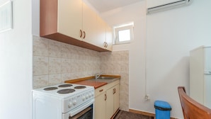 Una cocina compacta con estufa, fregadero y alacenas.