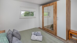 A bedroom with a bed, a wardrobe, a window, and a view of trees. - Beach front home in Karlobag with WiFi (Karlobag)