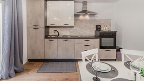 A modern kitchen with light wood cabinets, a black stove, and a stone backsplash. - Beach front home in Karlobag with WiFi (Karlobag)