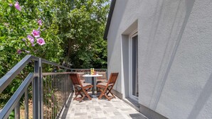 An outdoor patio with two wooden chairs and a small table, surrounded by a metal railing and a grey textured wall. - Beach front home in Karlobag with WiFi (Karlobag)