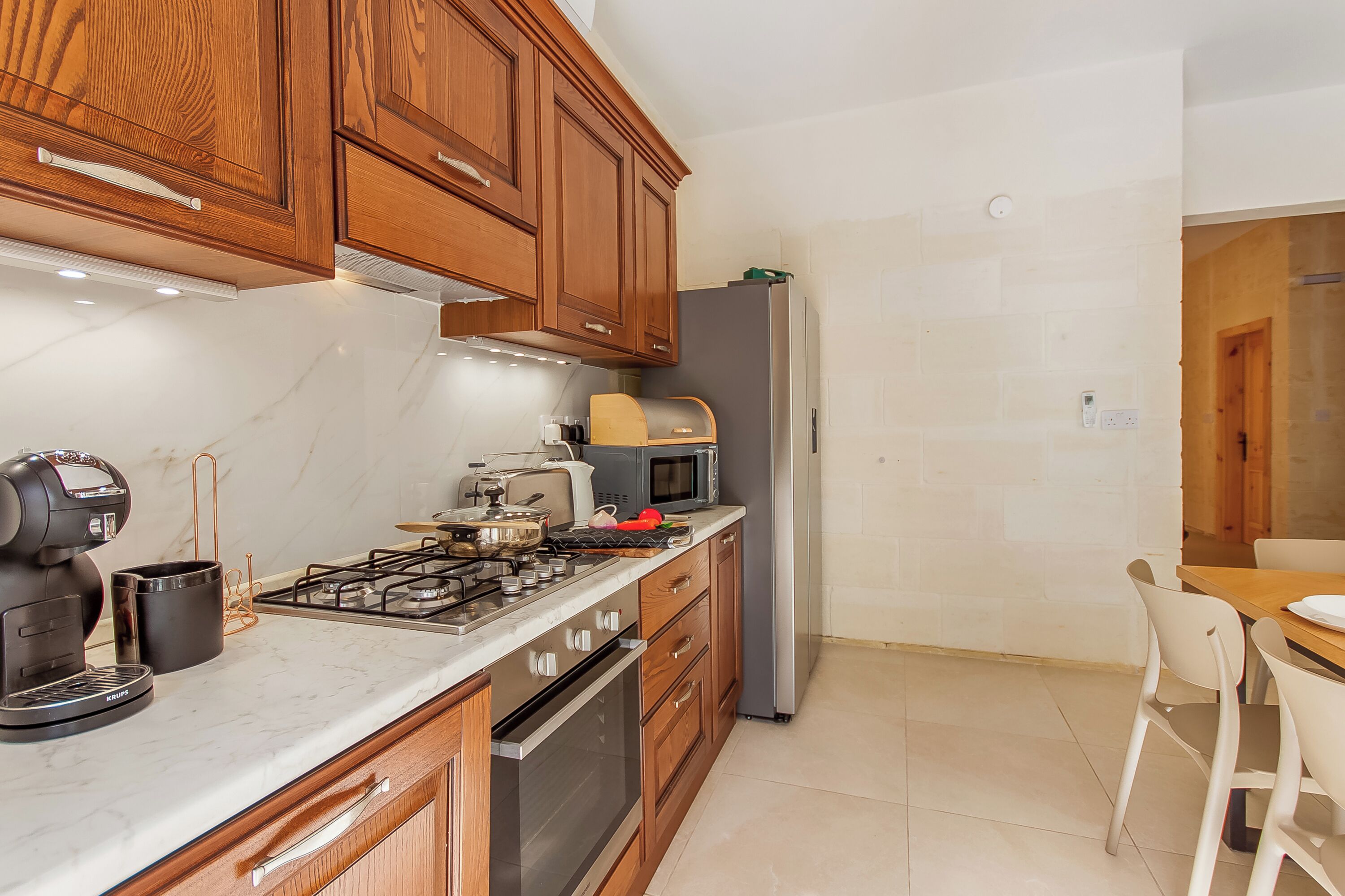 A modern kitchen with wooden cabinets, a gas stove, a microwave, and a refrigerator.