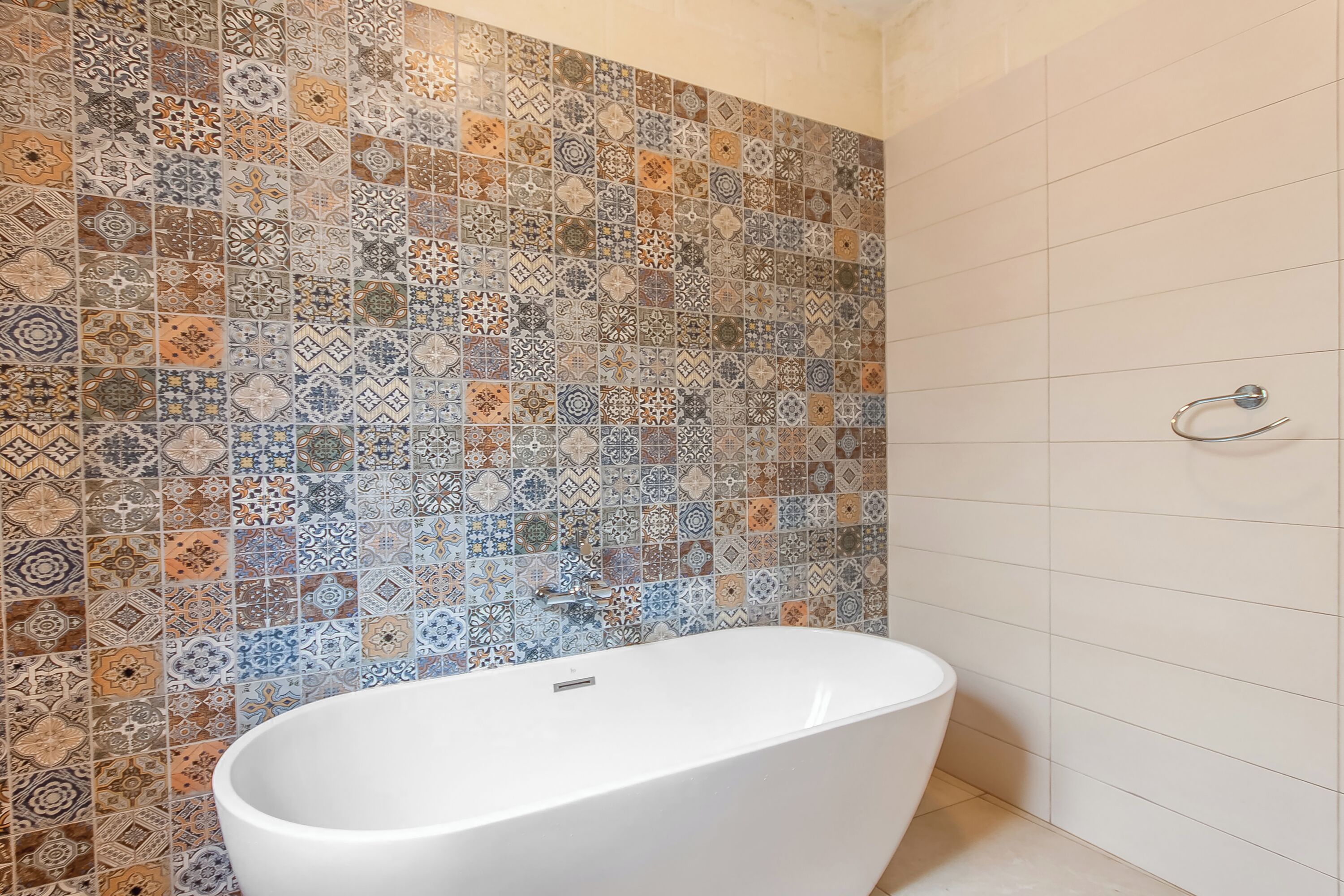 A bathroom with a freestanding bathtub, a tiled shower wall, and a white tiled floor.