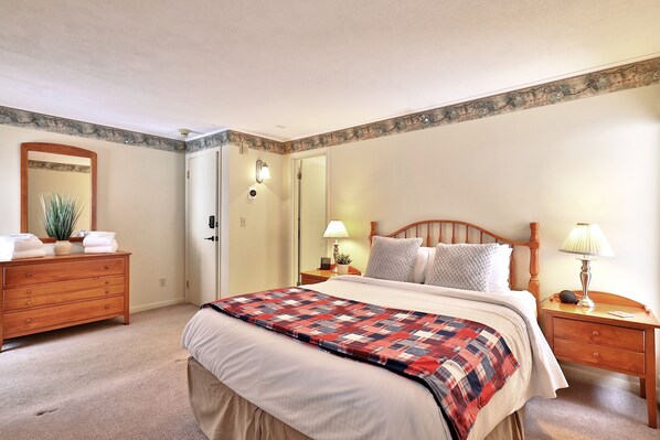 A bedroom with a bed, wooden nightstands, a dresser, a mirror, and a door. - The Birch Ridge: Mission Room #2 - Queen Suite In Renovated Killington Lodge. Hot Tubs. 1 Bedroom Home (Killington)