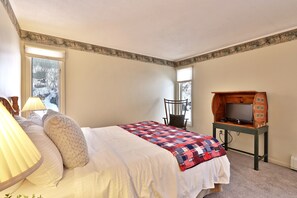 A bedroom with a bed, a television on a wooden stand, a lamp, and a window with a view of trees. - The Birch Ridge: Mission Room #2 - Queen Suite In Renovated Killington Lodge. Hot Tubs. 1 Bedroom Home (Killington)