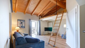 A living room with a blue sofa, a wooden ladder, and a television. - Cozy home in Albagnano di Bee with house sea view (Albagnano di Bee)