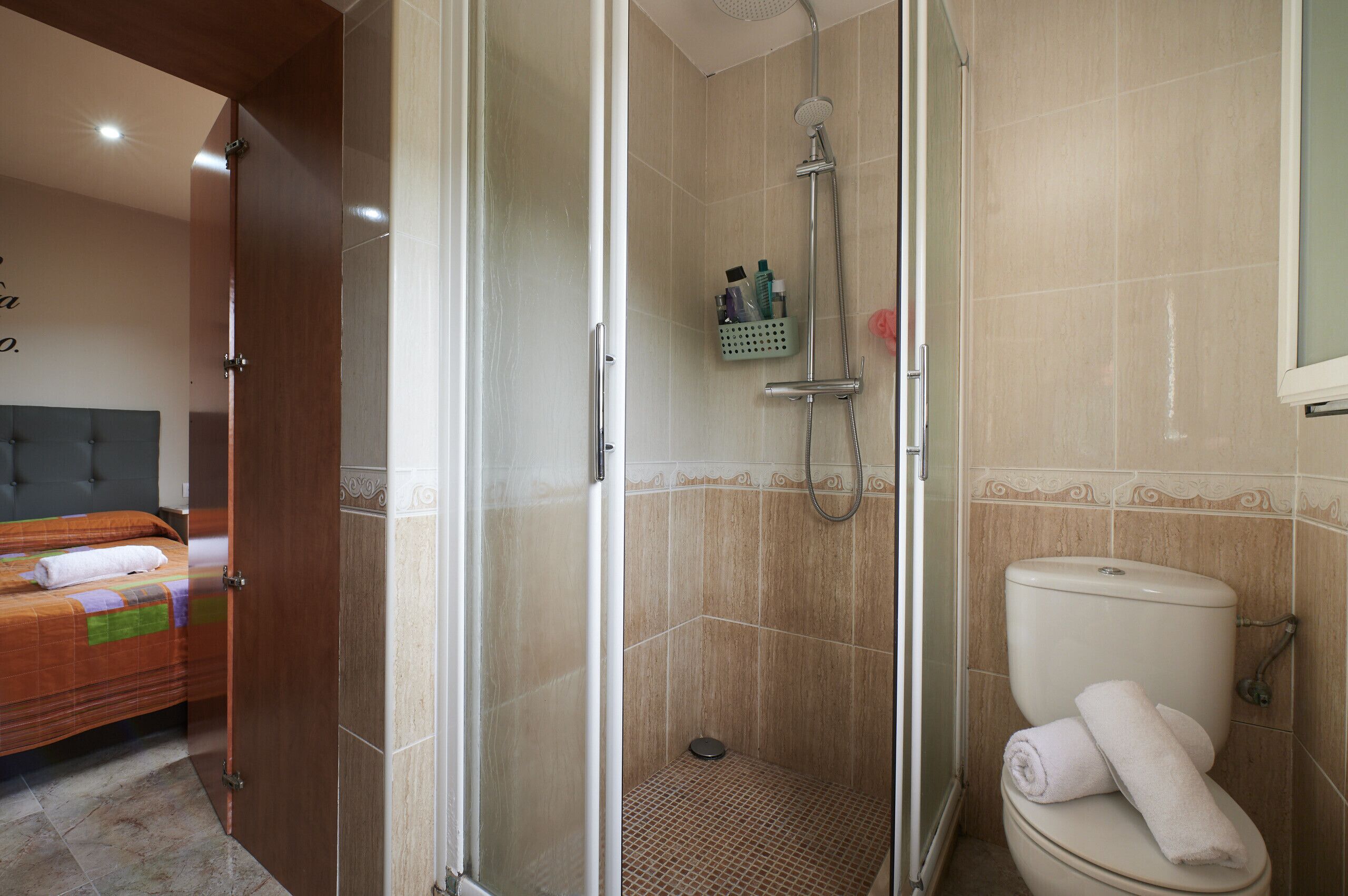 Ein Badezimmer mit Dusche, Toilette und einem Bett mit Handtuch.