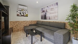 Una sala de estar moderna con un sofá seccional gris, una mesa de centro negra y un cuadro abstracto grande en la pared.